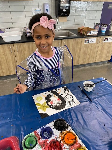 Illustrates a young child independently painting.
